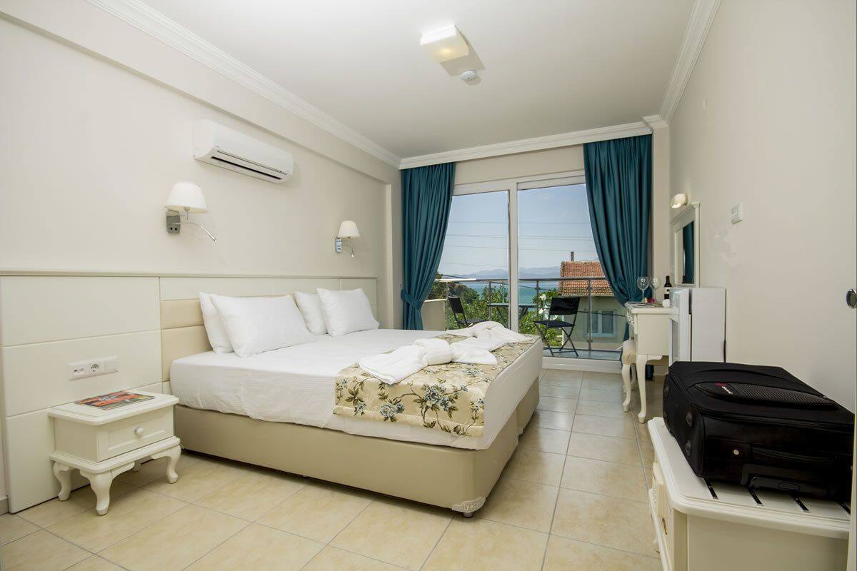 A hotel room with a bed, a nightstand, a desk, a chair, and a suitcase.