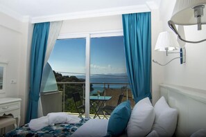 A hotel room with a bed, a desk, a chair, and a balcony with a table and chairs. - Sovalye Hotel (Fethiye)