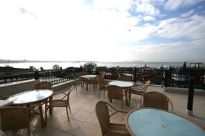 Una terraza al aire libre con mobiliario de mimbre y vistas al mar.