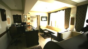 A living room with a sofa, a coffee table, a desk, and a television. - Grand Peninsula Hotel (Istanbul)
