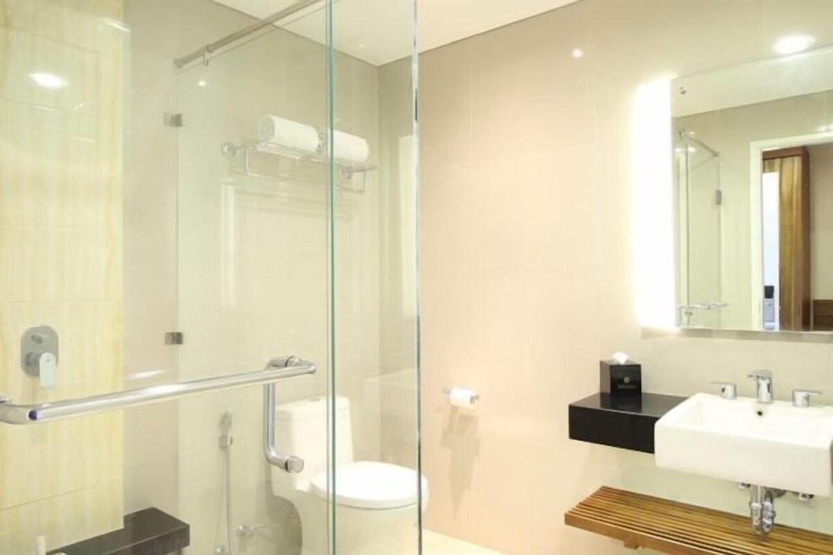 A modern bathroom with a glass shower enclosure, a toilet, a sink, and a mirror.