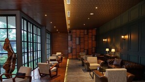 Un amplio vestíbulo con piso de madera, una gran escultura de árbol y un área de descanso con sofás y sillones.