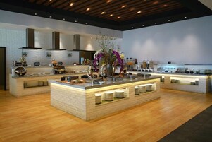 A modern kitchen with a central island, white brick walls, and wooden flooring.
