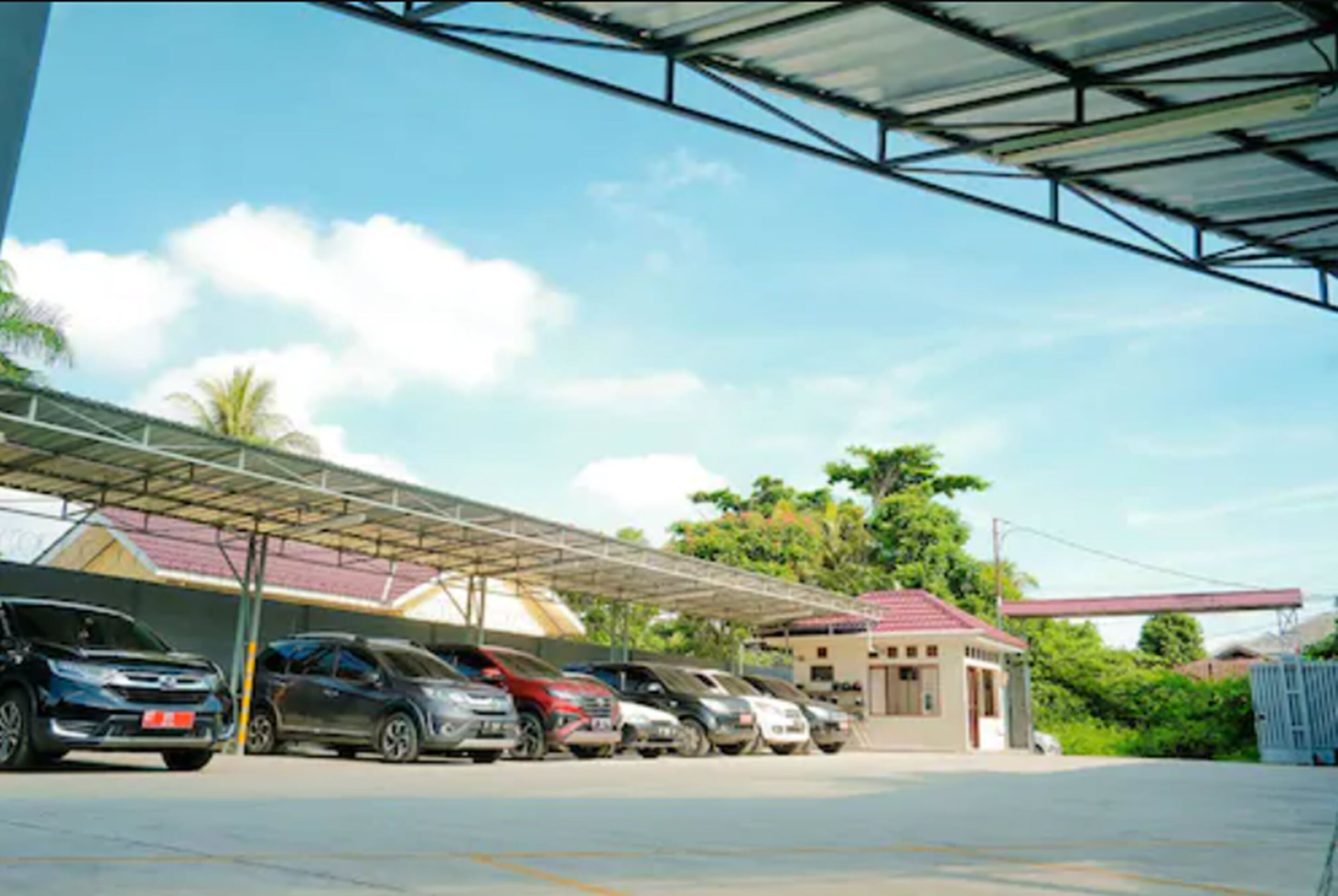 Un estacionamiento techado con varios coches aparcados bajo una cubierta metálica.