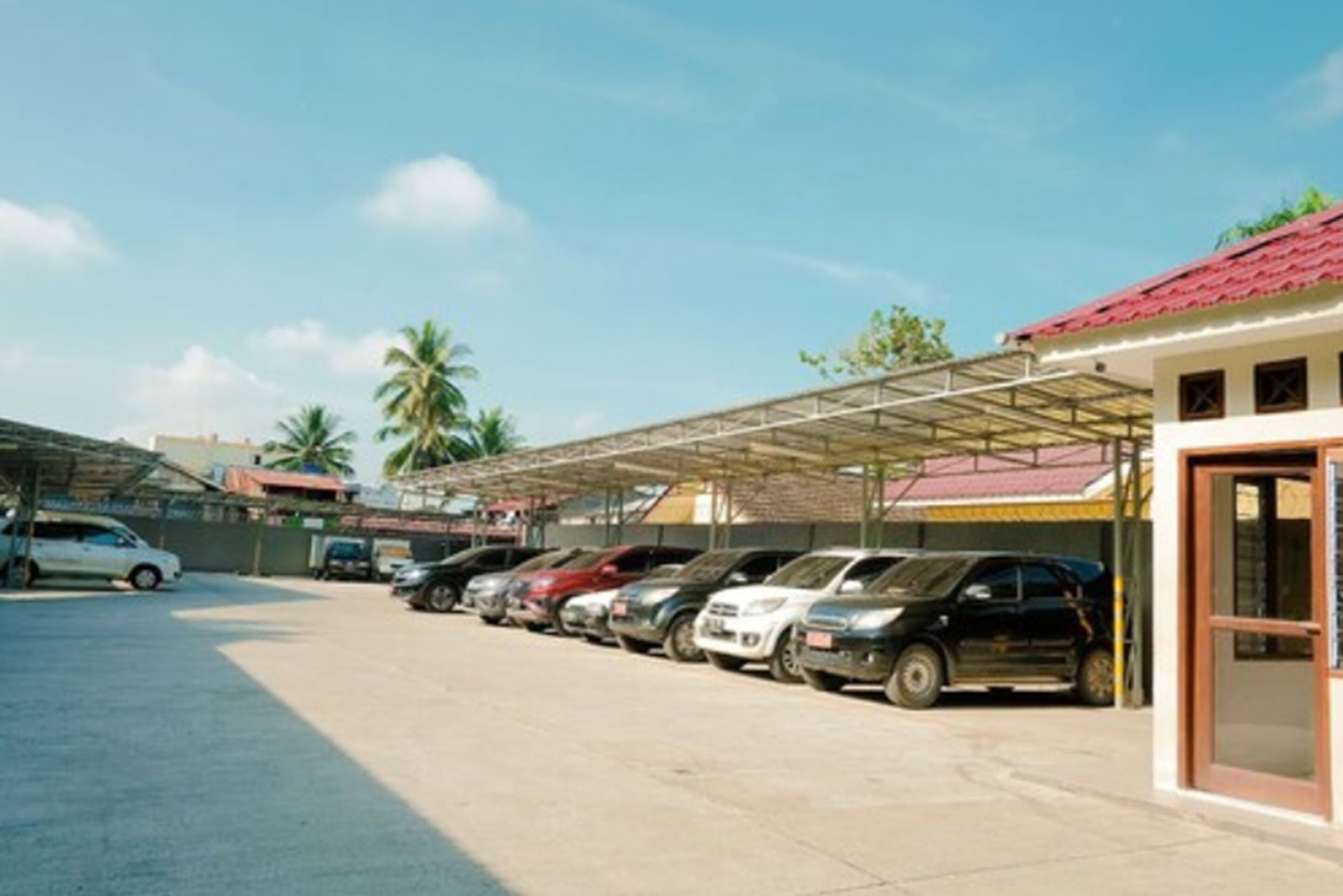 A parking area with multiple cars parked under a covered structure.