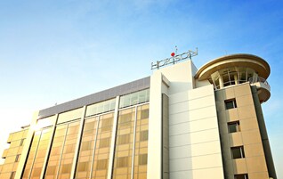Un hotel moderno con una torre de esquina curva, ventanas amplias y un cartel llamativo.
