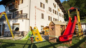 A building with a sign reading "Ristorante Manolo Baldo" and playground equipment outside. - Rifugio Monte Baldo (Avio)