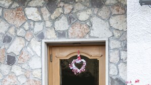 A stone wall, wooden door, and potted plants. - Rifugio Monte Baldo (Avio)