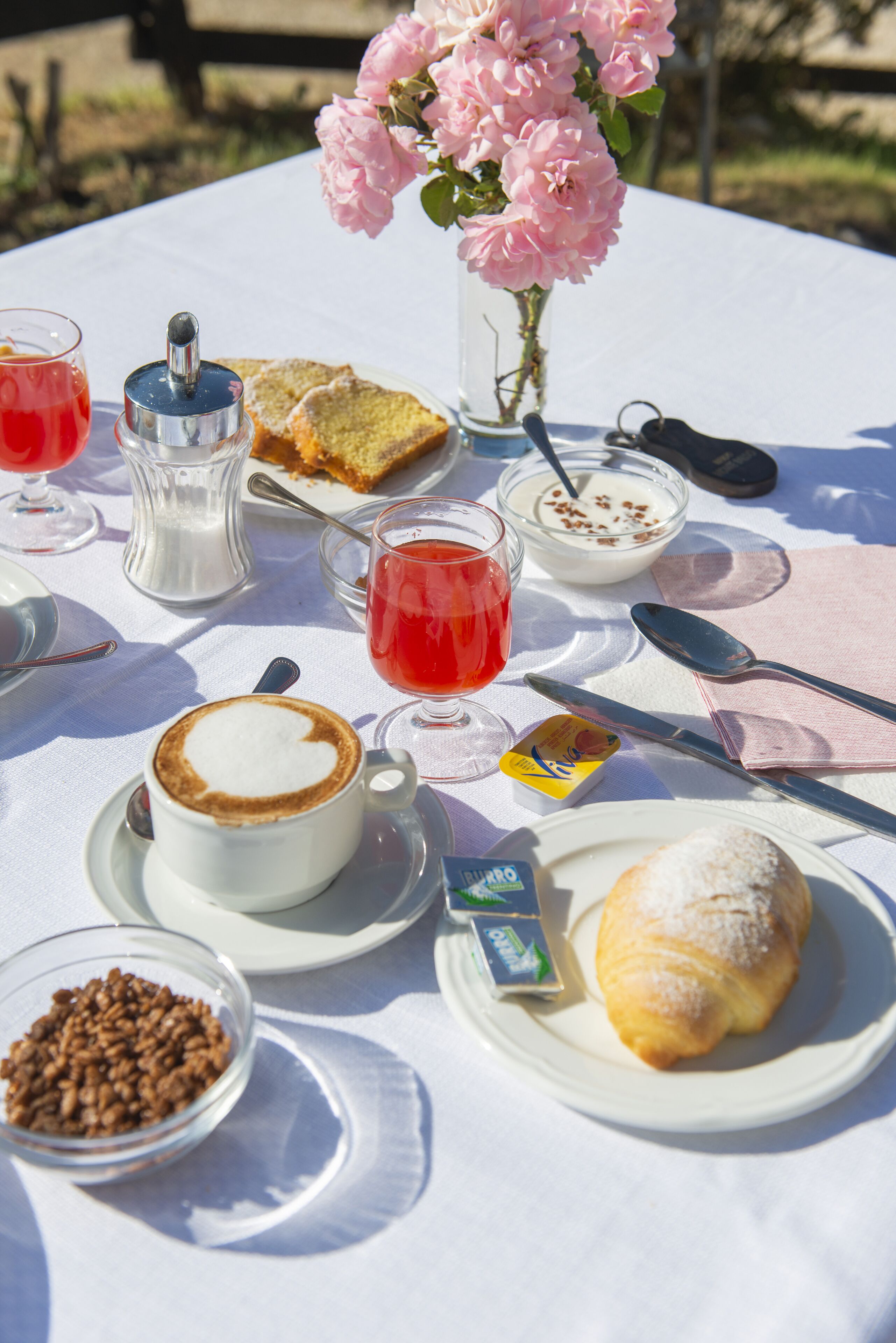 Ett bord dukat med ett urval av matvaror, inklusive bröd, bakverk och en croissant, samt koppar med kaffe och te.