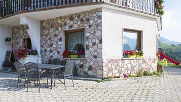 A stone building with a balcony, outdoor seating, and flower boxes.