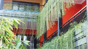 A building with a red exterior, black railings, and hanging greenery. - Rena Segara House Kuta (Kuta)