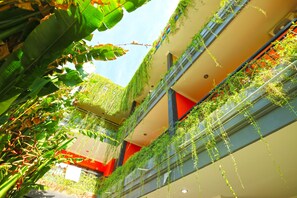 Un atrium à plusieurs niveaux, agrémenté de plantes suspendues et d’un mur d’accent de couleur rouge.