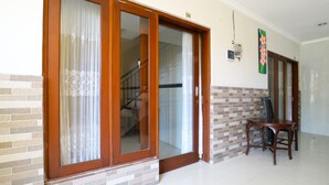 A room with a sliding glass door, a staircase, and a dining area with a table and chairs. - Rena Segara House Kuta (Kuta)