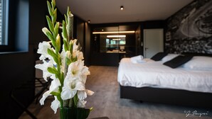 Un dormitorio moderno con una cama grande, una mesita de noche y un jarrón con flores blancas.