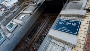 Señal de hotel con el nombre "La Reine Hotel Restaurant" y el número "86" en la fachada de un edificio.