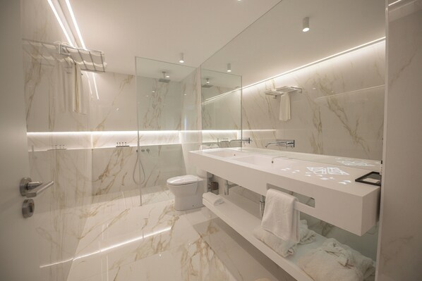 A modern bathroom with a glass shower enclosure, a white vanity with a large mirror, and marble flooring.