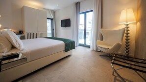 A hotel room with a bed, a chair, a TV, and a window with curtains. - Nacala Plaza Business Design Hotel (Nacala)