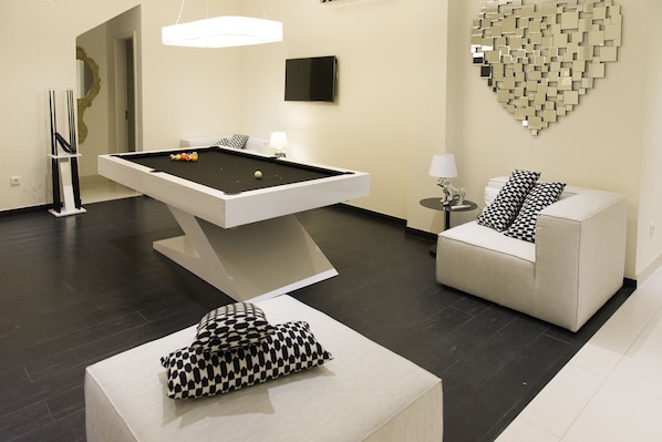 Ein moderner Raum mit Billardtisch, einer Couch und einer dekorativen Wanddekoration in Herzform.