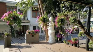 Un espace extérieur doté d’un sol carrelé, d’une sculpture blanche et de plantes en fleurs.