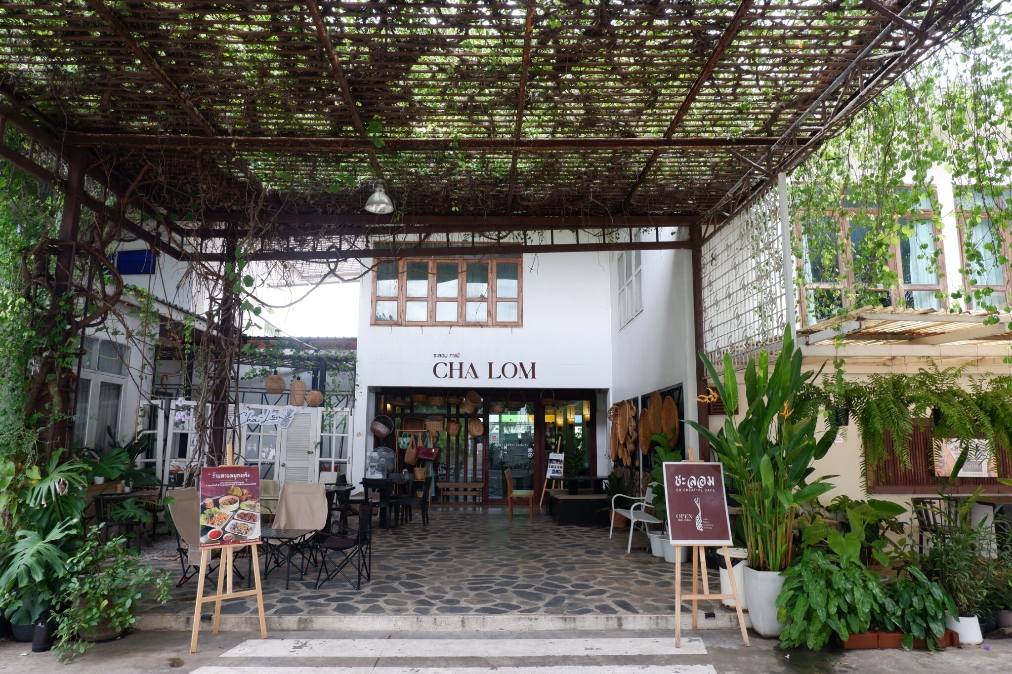 A cafe named 'CHA LOM' with outdoor seating, a covered entrance, and potted plants.
