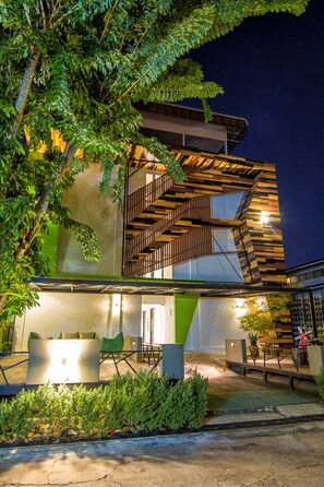 Een modern gebouw met een houten trap, een groene zitgedeelte en een goed verlichte entree.