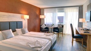 A hotel room with two beds, a desk, a chair, and a TV.