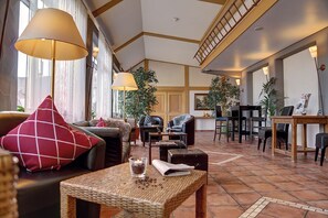 A spacious lobby with a high ceiling, a staircase, and a seating area with sofas and chairs. - Landhotel Krone  (Deggenhausertal)