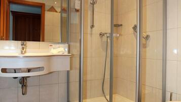 Ein Badezimmer mit einer Duschkabine, einem Waschbecken mit Spiegel und einer Toilette.
