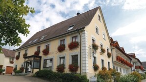 A traditional European hotel with a classic facade, multiple windows with flower boxes, and a sign indicating it is a restaurant.