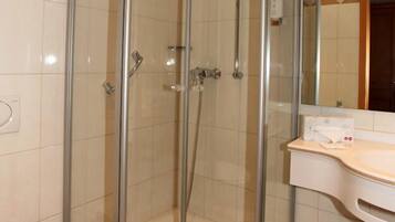 A glass-enclosed shower stall with a white sink and a mirror above it.