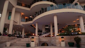 A multi-level hotel atrium with a central staircase, columns, and balconies with plants. - L'ancora Beach Hotel (Kemer)