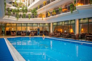 Una piscina interior con varios niveles de balcones, cada uno decorado con plantas y zonas de estar.