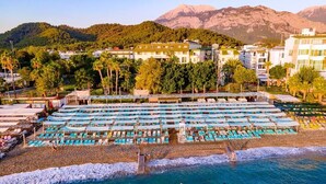 A beach resort with multiple swimming areas, a rocky shoreline, and buildings in the background. - L'ancora Beach Hotel (Kemer)