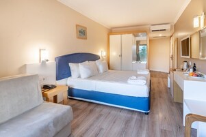 Habitación de hotel con cama, escritorio, silla, mesita de noche y aire acondicionado.