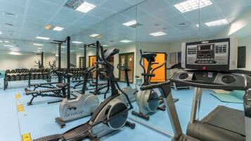 Une salle de sport équipée de divers appareils d’exercice, notamment des tapis de course, des appareils elliptiques et des appareils de musculation.