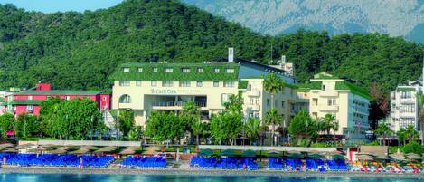 Un hôtel doté d’un toit végétalisé, d’un espace piscine avec des chaises bleues et offrant une vue sur les montagnes.