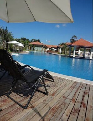 Een buitenzwembad, ligstoelen bij het zwembad