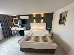 Una habitació d'hotel moderna amb un llit gran, una taula de treball i una cadira.