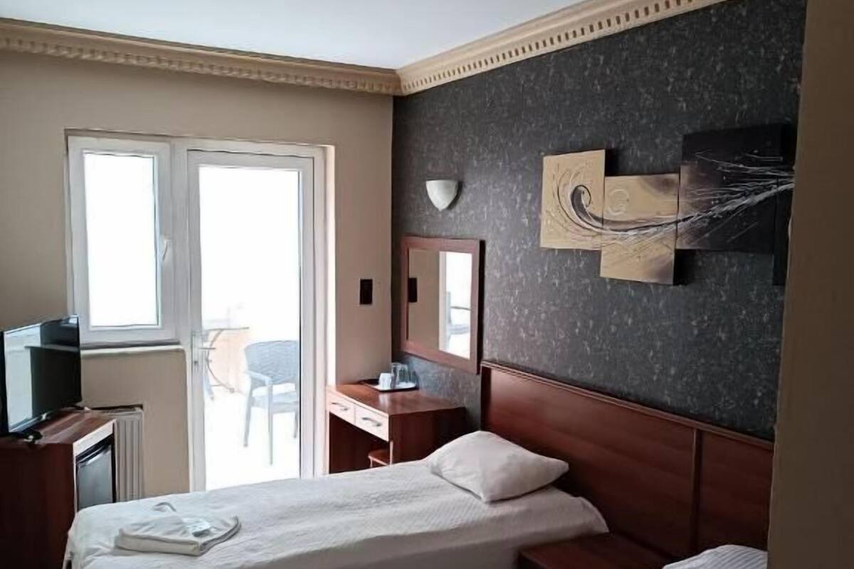 A hotel room with two beds, a desk, a television, and a window with a view.