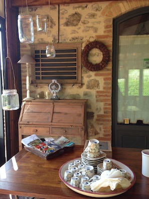 A rustic interior with a wooden table displaying a tray of tea cups and a stack of plates. - Il Borghetto Andrea Tafi (Lamporecchio)