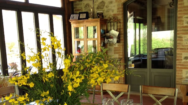 A wooden dining table with a potted yellow flower arrangement, a glass tray, and metal chairs. - Il Borghetto Andrea Tafi (Lamporecchio)