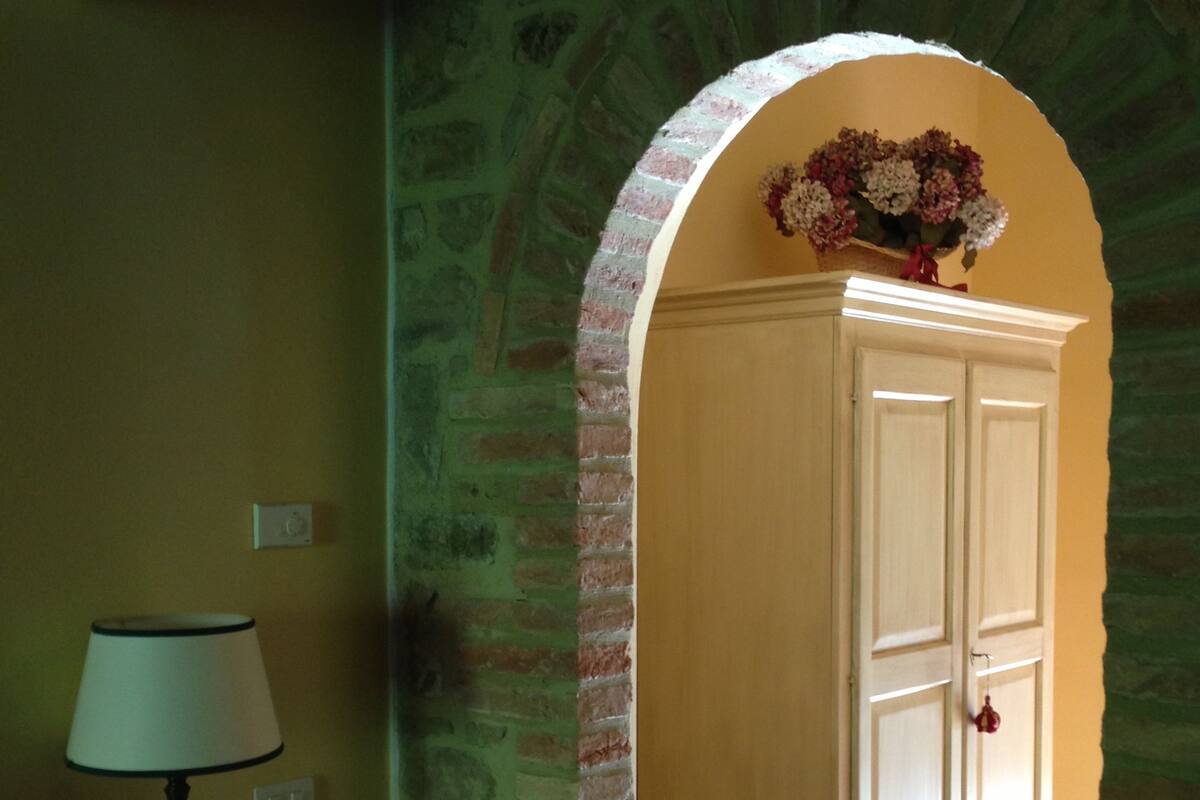 A room with a lamp, a cabinet, and a brick archway.