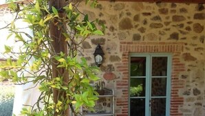 A stone building with a wooden pergola and a table with chairs. - Il Borghetto Andrea Tafi (Lamporecchio)