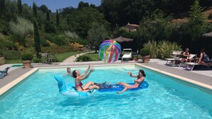 A swimming pool with inflatable floats, lounge chairs, and a tiki umbrella. - Il Borghetto Andrea Tafi (Lamporecchio)
