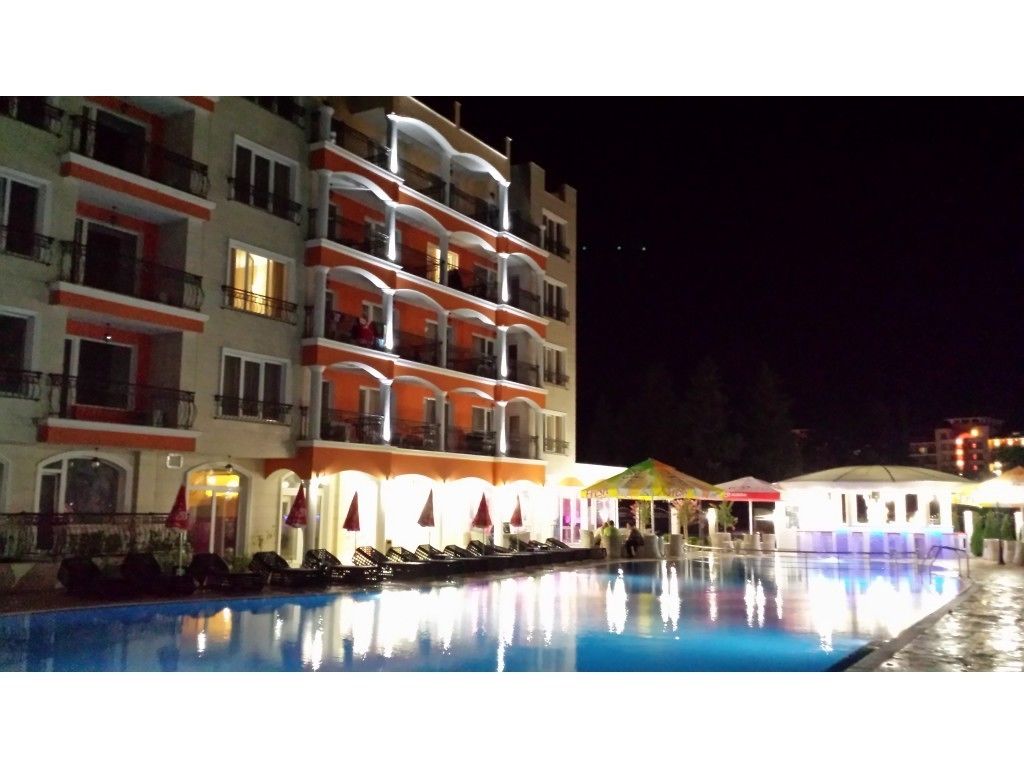 A multi-story hotel with balconies, a swimming pool, and outdoor seating areas.