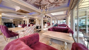 A luxurious interior with marble columns, plush seating, and a grand chandelier. - Avenue Deluxe (Sunny Beach)