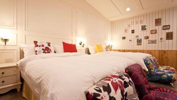 Un dormitorio con una cama grande, varios almohadones, una mesita de noche y una pared decorada con cuadros y un cartel.