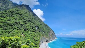 Paesaggio costiero con spiaggia e montagna.