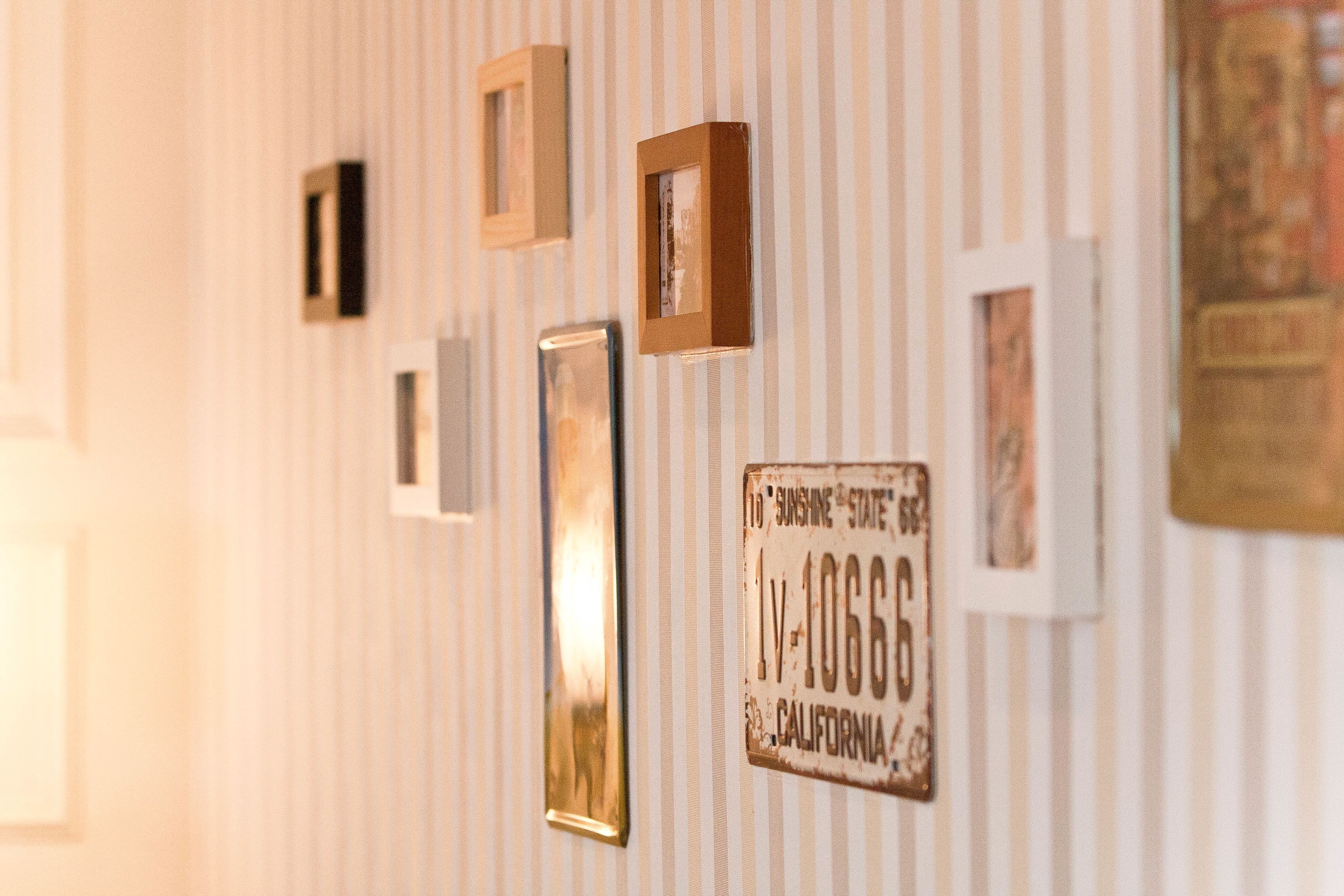 Una pared con varias fotografías enmarcadas y una placa de matrícula antigua.