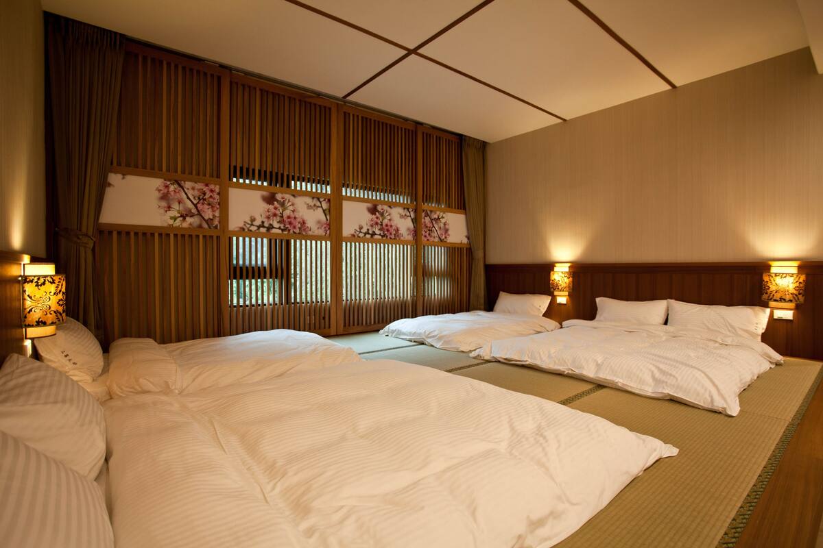 Ett hotellrum med två sängar, en skärm av trä i japansk stil (shoji) och väggmonterade lampor.